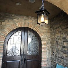 a light hanging from the side of a door in front of a brick wall with a bench underneath it