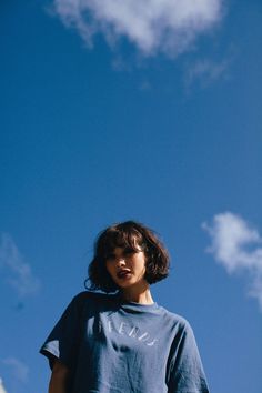 a person standing in front of a blue sky with white clouds and a frisbee