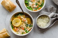 two bowls filled with soup and topped with parmesan sprinkles next to rolls