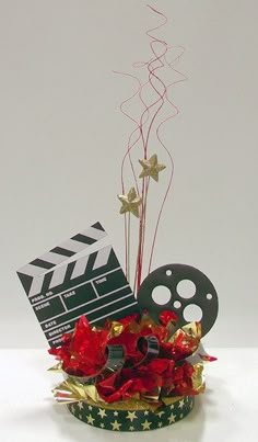 a film clapper and some red flowers in a small cup with streamers on it