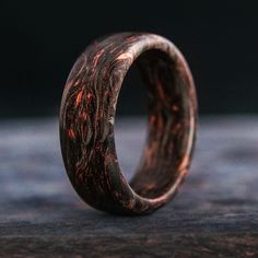 a wooden ring with red and black streaks on it's side, sitting on a table