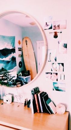 there is a mirror on the wall above a dresser and a surfboard in front of it