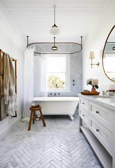 a bathroom with a white tub and wooden stools in front of the window, along with a large mirror on the wall