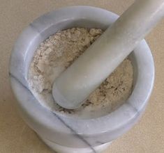 a mortar and powder in a bowl with a large white pipe sticking out of it