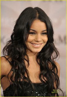 a woman with long black hair smiling at the camera and wearing a sequin dress