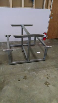 a metal structure sitting on top of a cement floor next to a white wall and red fire hydrant