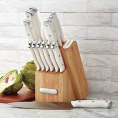 there are many knives that are on the cutting board next to some artichokes