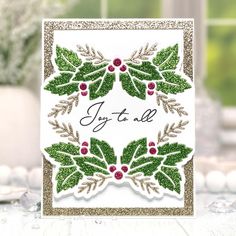 a christmas card with holly leaves and red berries on it, says joy to all