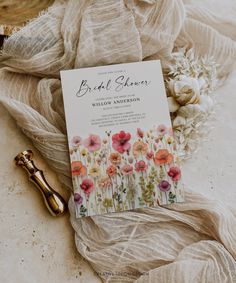 a book sitting on top of a white cloth next to a golden key and some flowers