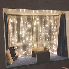 a window with lights on it and a teddy bear sitting in the window sill