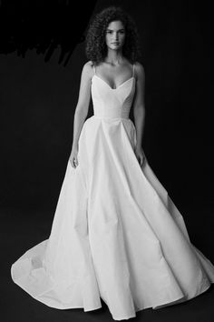 a black and white photo of a woman in a wedding dress with her hands on her hips