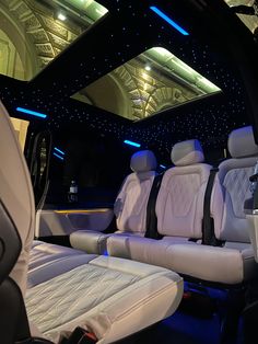 the interior of a car with white leather seats and blue lights on the ceiling is lit up