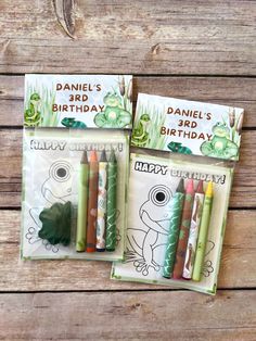 three children's birthday cards with crayons in them on a wooden surface