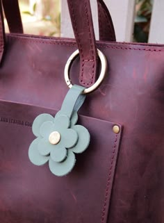 a handbag with a flower on the front and a metal ring at the bottom