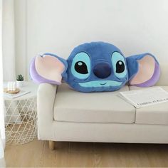 a blue and purple stuffed animal sitting on top of a white couch