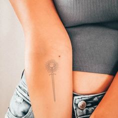 a woman's arm with a tattoo on it that has a small sunflower