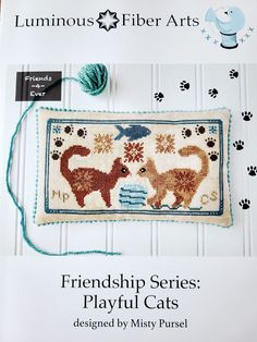 a cross stitch book with an image of two cats and a cat's paw