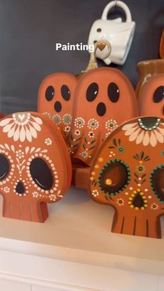 painted sugar skulls sitting on top of a white shelf next to a purse and keychain