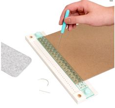 a person cutting paper with a pair of scissors and a piece of felt next to it