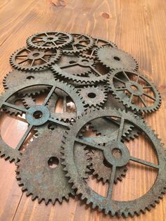 several rusty gears on a wooden surface with one missing the gear wheel and another missing the clock face