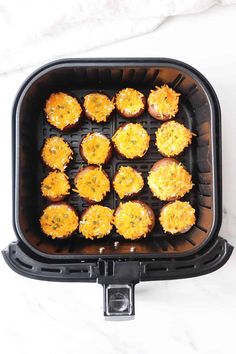 an air fryer filled with cooked food on top of a white counter