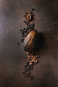 some coffee beans and other things on a dark surface with a spoon in the middle