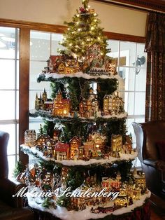 a christmas tree decorated with miniature houses and lights