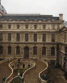 an old building with steps leading up to the top floor and two large buildings in the background