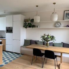 a kitchen and living room with white walls, wood floors and open shelving on the wall