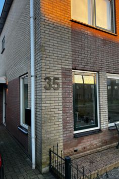 a red car parked in front of a brick building with the number 35 on it