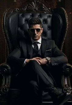 a man in a suit and sunglasses sitting on a chair