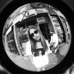 a woman wearing sunglasses standing in front of a store