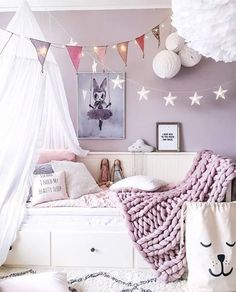 a bedroom decorated in pastel colors with white and pink accessories on the ceiling, bedding, rugs and pillows