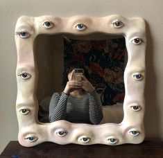 a woman taking a selfie with her cell phone in front of a decorative mirror