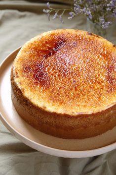 a cake sitting on top of a white plate next to a vase with purple flowers