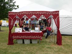 two women sitting at a table under a red canopy with pictures on it in front of them