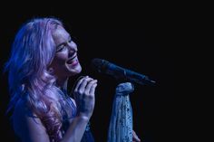 a woman with pink hair singing into a microphone