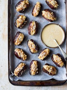 baked stuffed dates with dipping sauce on a baking sheet