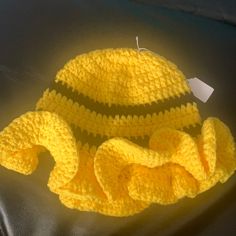 a crocheted yellow hat and blanket on a black surface