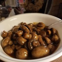 a white bowl filled with mushrooms covered in brown gravy on top of a table