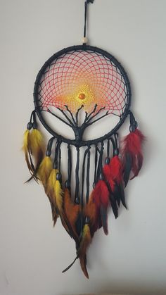 a dream catcher with feathers hanging from it's side and a tree in the center