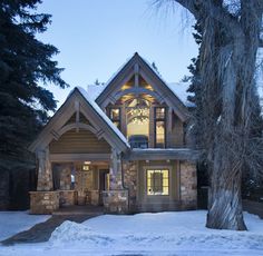 a large house with snow on the ground and trees in front of it at night