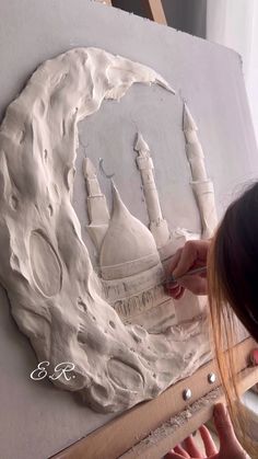 a woman is working on an art project with white paint and paper machs in front of her