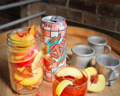 a wooden table topped with glasses and jars filled with fruit next to cans full of drinks