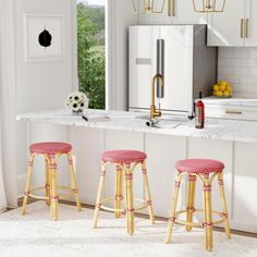 two stools in front of a kitchen island with white countertops and gold accents