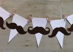 three paper buntings with brown mustaches hanging from them on a wooden table