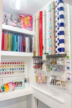 an organized craft room with lots of different colored papers and supplies on shelving units