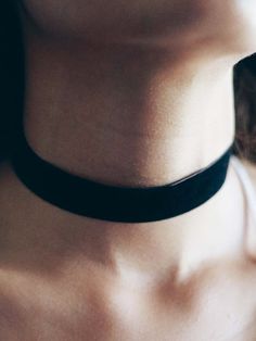 a close up of a person wearing a black choker with no shirt on it