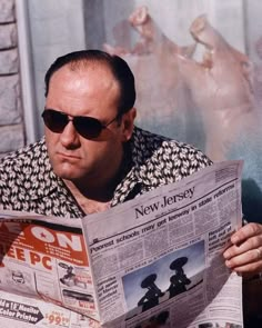 a man reading a newspaper while wearing sunglasses