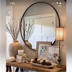 a mirror sitting on top of a wooden table next to a vase filled with flowers